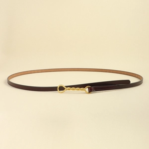 Dettaglio sottile cintura in pelle bordeaux con fibbia dorata a infinito su fondo beige