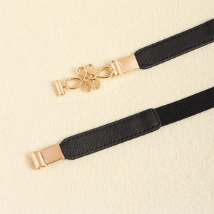 Women's black elastic waist belt featuring a gold Chinese knot buckle on a beige base