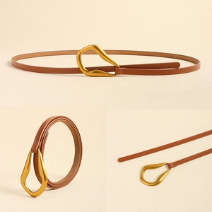 Détail d'une ceinture fine en cuir marron avec une boucle dorée irrégulière texturée