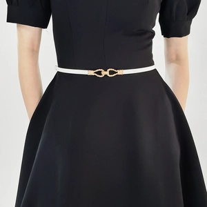 Detail of white thin fashion belt with golden interlocking buckles on black dress