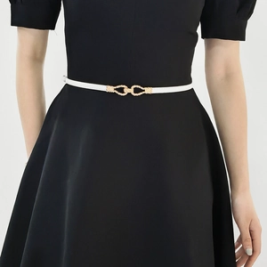 Detail view of white leather waist belt featuring a gold geometric braided metal buckle