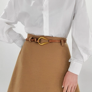Vue détaillée d'une ceinture fine en cuir marron foncé avec boucle en métal doré