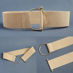 Detail view of beige elastic waist belt featuring a large gold O-ring buckle closure