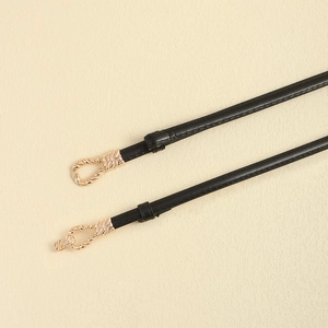 Close-up of thin black leather belt with textured gold knot buckle for dresses