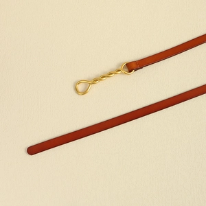 Dettaglio della cintura in pelle caramello con fibbia decorativa in metallo dorato
