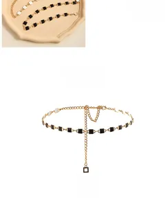 Detail of golden metal waist chain featuring black and white square enamel elements