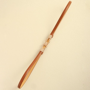 Close-up of slim brown leather belt featuring a twisted gold metal buckle for dresses