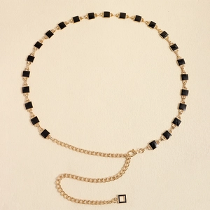 Detail of gold metal waist chain with black square enamel blocks and adjustable lobster clasp
