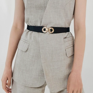 Close-up of a slim black leather belt featuring an elegant interlocking gold metal buckle
