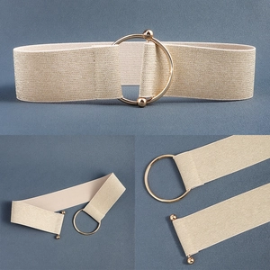 Detailed view of beige elastic waist belt featuring a large gold circular metal buckle