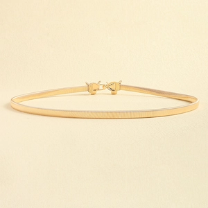 Detail of golden metal elastic waist belt featuring a vintage lion head buckle design