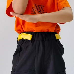 Detail eines orangen T-Shirts mit COOL DANCE Aufdruck und schwarzer Shorts mit Klettverschluss