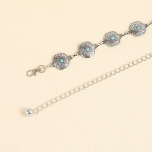 Détail d'une chaîne de taille argentée vintage avec perles turquoise et fleurs ciselées