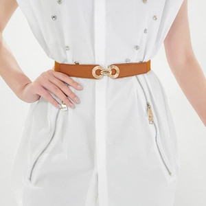 Detail of tan elastic belt with gold double-ring buckle shown on a model