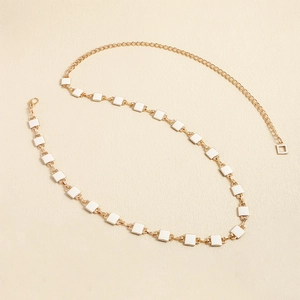 Close-up of minimalist gold metal waist chain with white enamel square beads and lobster clasp
