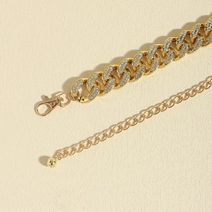 Close-up detail of golden iced-out Cuban link waist chain with sparkling rhinestones and clasp