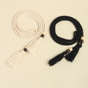 Detail of woven rope belts with cream and black tassels featuring decorative wooden beads