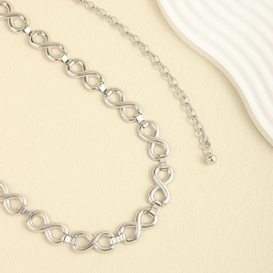 Macro view of silver infinity link chain belt with polished finish on beige leather