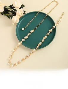 Détail d'une ceinture chaîne dorée à feuilles et perles sur un plateau décoratif