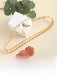 Dettaglio della catena dorata da vita con doppi cuori in smalto bianco e maglia a molla