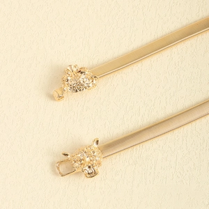 Detail of golden elastic spring belt with vintage leopard head buckle and metal mesh texture