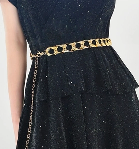 Nahaufnahme der goldenen klobigen Acryl-Metall-Kettengürtel an einem schwarzen Paillettenkleid