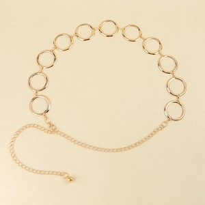 Détail d'une ceinture chaîne en métal doré avec anneaux circulaires et fermoir mousqueton