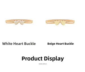 Dettaglio delle fibbie a doppio cuore su cinture elastiche in metallo bianco e beige