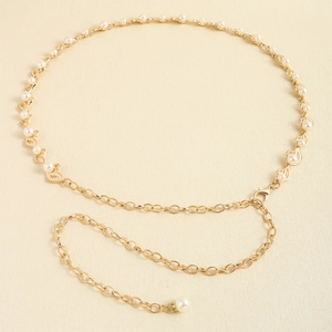 Détails d'une chaîne de taille dorée ornée de perles blanches et fermoir mousqueton chic