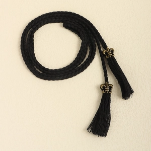 Detailed close-up of woven rope belt with tassel ends and vintage bronze fleur-de-lis charms