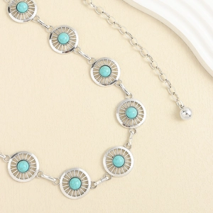 Détail de la ceinture en métal vintage avec incrustation de turquoise et motif soleil