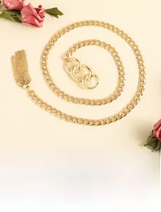 Détail de la chaîne de taille dorée avec gland et anneaux réglables sur fond beige