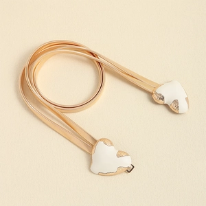 Close-up of gold spring waist chain featuring a white double heart enamel buckle detail