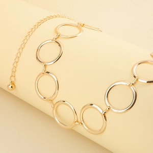 Détail d'une ceinture chaîne dorée à maillons circulaires avec pendentif boule réglable