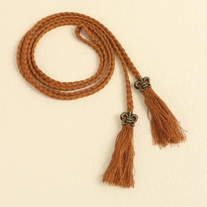 Detail of bohemian braided rope belt with bronze iris metal charm and elegant fringe
