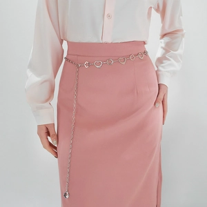 Détail d'une ceinture chaîne argentée avec motifs de cœurs et fleurs sur une jupe rose