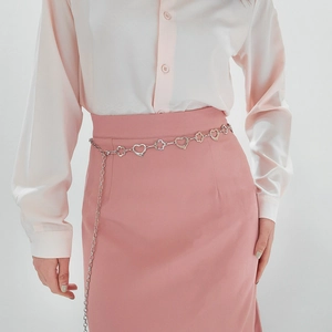 Détail de ceinture chaîne argentée avec maillons cœur et fleur sur jupe rose