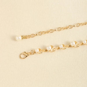 Détails macro d'une ceinture chaîne dorée avec breloques feuilles et perles pour robes