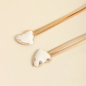 Detail of gold spring waist chain featuring a white heart-shaped buckle and metal texture