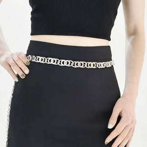 Detail of elegant gold and silver interlocking metal ring waist chain on black dress