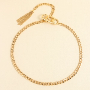 Détail d'une chaîne de taille dorée avec maillons cubains et pendentif à pampilles
