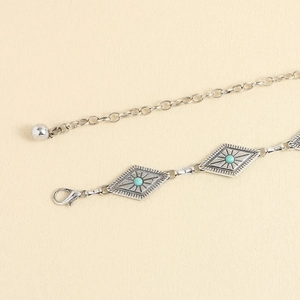 Détail d'une chaîne de taille argentée rétro avec perles turquoise et plaques en losange