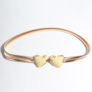 Dettaglio della cintura a molla doppia con fibbie a cuore crema e finitura in metallo oro