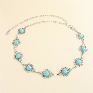 Détail d'une chaîne de taille bohème argentée avec turquoises et motifs floraux