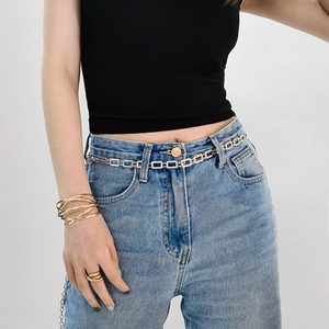 Vue détaillée d'une ceinture chaîne argentée à maillons rectangulaires portée par un mannequin