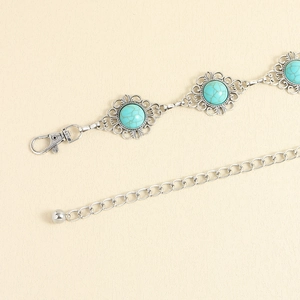 Détail d'une chaîne argentée vintage avec des pierres de turquoise et motifs ajourés