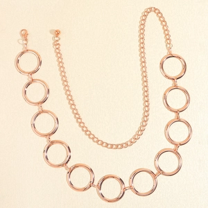 Détail de la ceinture chaîne en métal or rose avec anneaux circulaires et fermoir mousqueton