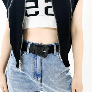 Detail of black textured Y2K waist belt with vintage buckle on light blue denim jeans