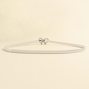 Close-up of silver elastic metal belt with rhinestone bow buckle on beige texture