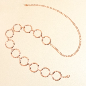 Détail d'une chaîne de taille en métal rose doré avec de grands cercles géométriques